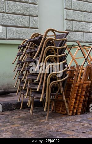 sedie ripiegate. tavoli in acciaio inossidabile lucidati di fronte a un bar bagnato da pioggia e rugiada. la stagione delle terrazze all'aperto termina. Foto Stock