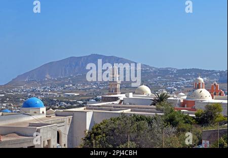 Grecia, Isola di Santorini: Vista su Fira, con la torre dell'orologio e la cupola della cattedrale cattolica e il Monte Profitis Ilias in lontananza. Foto Stock