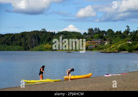 Cile. Puerto Varas: Bagnanti sulla spiaggia sabbiosa del lago Llanquihue, con il vulcano innevato, Osorno, (2652 m.), in lontananza. Foto Stock