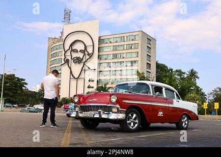 Vettura classica vintage Chevrolet su Piazza della Rivoluzione contro la costruzione del Ministero dell'informazione e delle comunicazioni con Camilo Cienfuegos ritratto Foto Stock