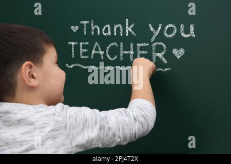 Cute Little boy frase scritta grazie insegnante sulla lavagna verde Foto Stock
