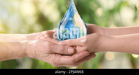 Giornata mondiale dell'acqua. Donne giovani e anziane che detengono l'icona della goccia con l'immagine della Terra all'interno su sfondo verde sfocato, primo piano Foto Stock