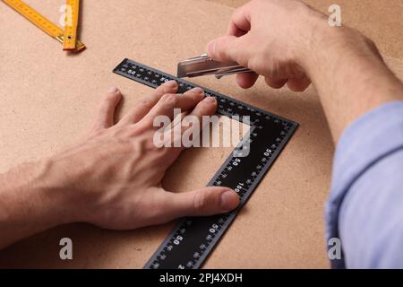 Uomo che taglia il bordo del truciolo con il coltello di utilità ed il righello, primo piano Foto Stock