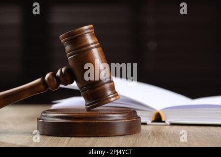 Gavel di legno e libro aperto sul tavolo su sfondo scuro. Spazio per il testo Foto Stock