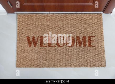 Tappetino della porta con parola DI BENVENUTO vicino all'entrata, vista dall'alto Foto Stock