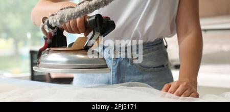 Vista in primo piano della lavanderia da stiro femminile, design per striscioni. Servizio di lavaggio a secco Foto Stock