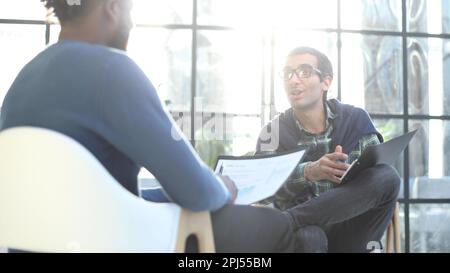 L'uomo d'affari premuroso in carta d'attesa del formalwear mentre si siede alla sedia compila un questionario del resume in ufficio Foto Stock