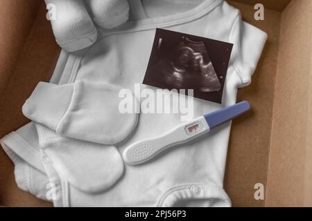 Scatola con il roba del bambino ed il test di gravidanza. Foto Stock