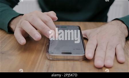Smartphone man hand holding con app per il trading di titoli in valuta sullo schermo. Azioni di analisi finanziaria. Foto Stock