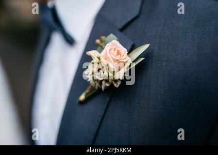 Un uomo che indossa un abito formale con un fiore rosa sul reverse Foto Stock