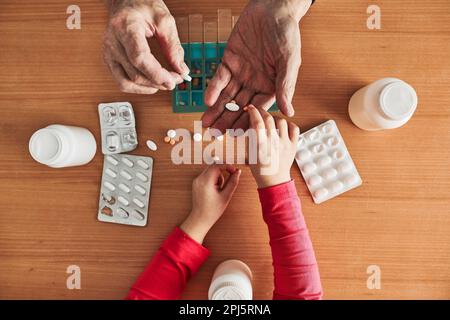 Nipote aiutare nonno per organizzare farmaci in dispenser di pillole. Uomo anziano che prende le pillole dalla scatola. Assistenza sanitaria e concetto di vecchiaia con medic Foto Stock