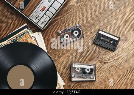 Dischi in vinile, cassette e registratore su tavolo di legno. Stile di musica retrò. 80s festa musicale. Stile vintage. Apparecchiature analogiche. Audio stereo Foto Stock