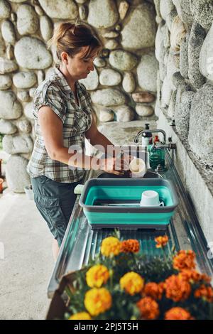 Donna che lava i piatti pentole e piatti nella cucina all'aperto durante le vacanze in campeggio. Vita in campo Foto Stock