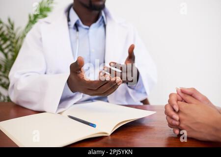 Primo piano delle mani dei medici che spiegano al paziente durante il controllo di gruppo Foto Stock