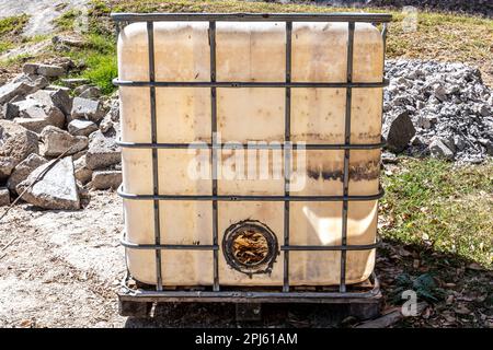 Primo piano di un vecchio e rotto magazzino contenitori in plastica con struttura metallica su un terreno sassoso con erba sullo sfondo, illuminato dalla luce del sole, dr Foto Stock