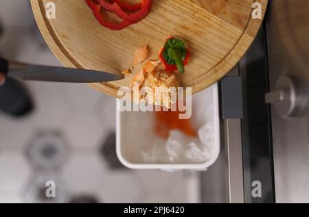 Il cuoco gettando rifiuti alimentari compostabili in un cestino bokashi per il riciclaggio. Persona ha messo i residui in un contenitore di composto per fermentazione Foto Stock