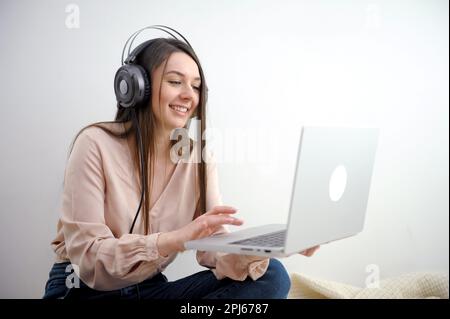 Donna in viaggio d'affari che indossa cuffie bianche per videochiamare al lavoro. Foto di alta qualità Foto Stock