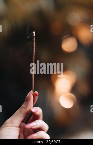 Mano femmina che tiene incenso bruciante. Fumo aromaterapico Foto Stock