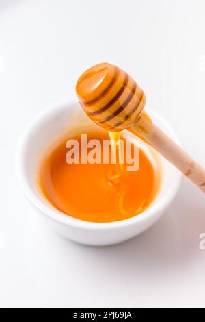 Miele con cucchiaia di miele in legno su sfondo bianco Foto Stock