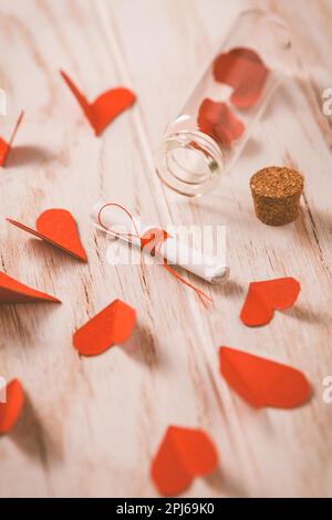 Messaggio d'amore in bottiglia con cuori di carta su legno Background - buon San Valentino Foto Stock