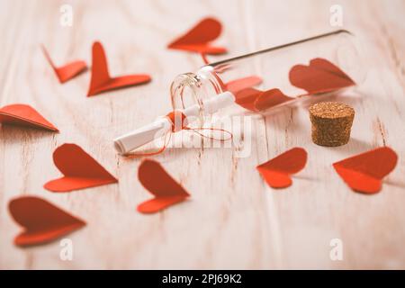 Messaggio d'amore in bottiglia con cuori di carta su legno Background - buon San Valentino Foto Stock