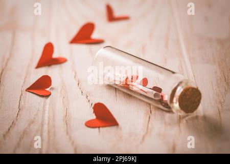 Messaggio d'amore in bottiglia con cuori di carta su legno Background - buon San Valentino Foto Stock