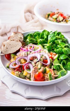 Insalata di tonno con cetriolo, cipolla rossa, insalata di mais, pomodori ciliegini e spezie. Cibo fatto in casa. Concetto per un pasto gustoso e sano Foto Stock