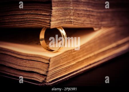 Anello d'oro tra le pagine del vecchio libro in stile vintage, primo piano, soft focus Foto Stock