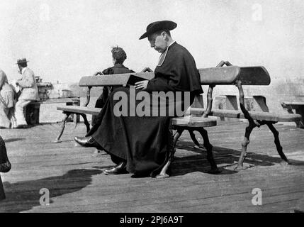 Sacerdote cattolico con cassock e cappello Saturno libro di lettura bibbia a Calais, Francia 1895 sacerdote francese padre Francais Europa 19th ° secolo Foto Stock