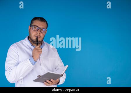 ritratto del giovane medico che ascolta i suoi pazienti su sfondo blu. concetto di visita del medico Foto Stock