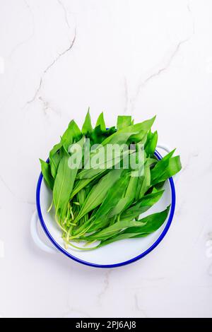 Aglio selvatico (allio ursinum) - mazzo di Ramson o porro d'orso in ciotola su fondo bianco Foto Stock