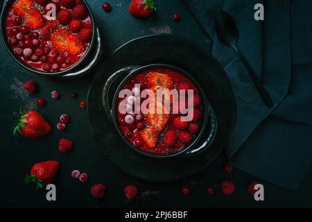 Prima colazione ciotola frullato rosso con semi di chia, fragola, lampone e ribes rosso su sfondo nero Foto Stock