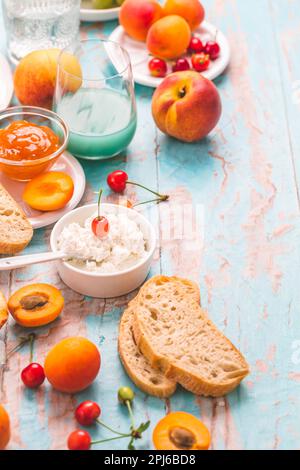 Ricotta con confettura di pesche e albicocche, ciabatta, frutta e frullato. Spuntino estivo Foto Stock