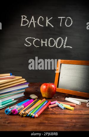 Mucchio di libri e esercizi con la scuola si applica e spuntino di mele con lavagna. Concetto di ritorno a scuola Foto Stock