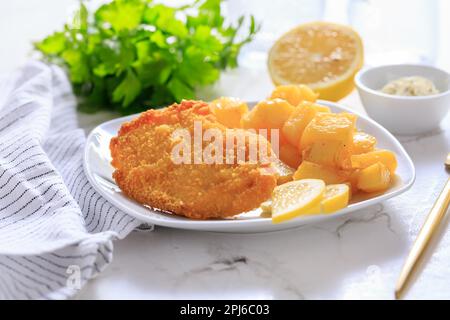 Scaloppa di pollo fatta in casa con patate al forno, maionese e limone Foto Stock