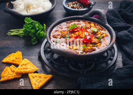 Ciotola di peperoncino con carne con riso e condimenti su tavola di legno Foto Stock