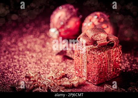 Ornamenti di brillantini natalizi e scatola presente su sfondo scuro Foto Stock