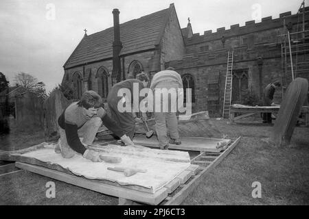 1986, storico, fuori nei terreni di una chiesa, i tetti che lavorano su lunghezze di piombo per riparare il tetto di una chiesa, Inghilterra, Regno Unito, martellando fuori i lati del materiale. Data la sua elevata malleabilità e il fatto che è molto lunga, il piombo è stato utilizzato per secoli su chiese e altri edifici storici. Foto Stock