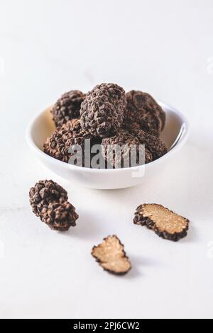 Tartufo nero in ciotola su fondo bianco, delicatezza di cottura Foto Stock