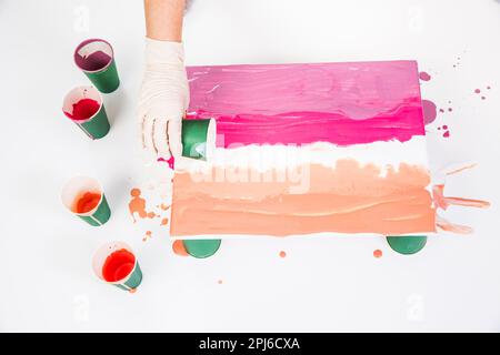 Tecnica di colata acrilica - Foto di azione di colata acrilica di vernice spalmata su tela con tazza Foto Stock