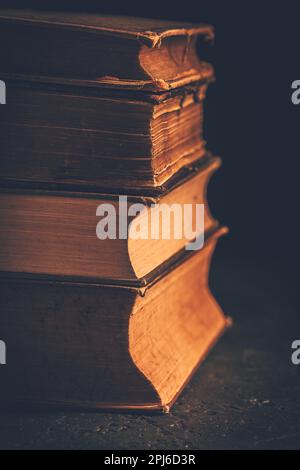 Pila di libri antichi rilegati in pelle su sfondo scuro Foto Stock