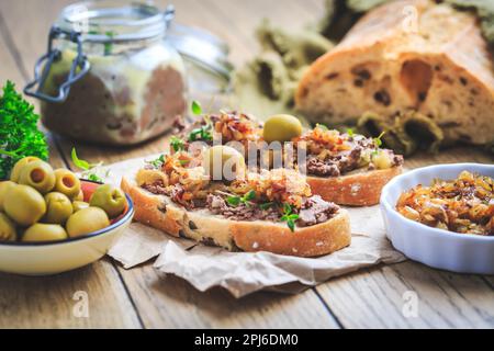 Patata fresca fatta in casa di fegato di pollo su pane ciabatta con cipolle arrostite e olive su tavola di legno Foto Stock