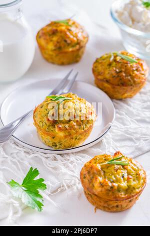 Deliziosi muffin caserecci di zucchine con formaggio feta sul tavolo da cucina bianco Foto Stock