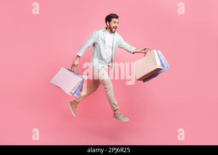 Foto a tutta lunghezza di un ragazzo funky positivo vestito maglietta teal jumping alta tenuta occasioni isolato sfondo di colore rosa Foto Stock
