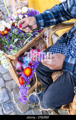 Europa, Portogallo, Obidos. Aprile 16, 2022. Merchant facendo fioriture fasce e decorazioni dei capelli. Foto Stock