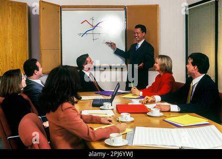 1996 STORICI IMPIEGATI CHE SI RIUNISCONO INTORNO AL TAVOLO Foto Stock