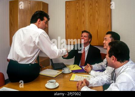 1996 STORICO HANDSHAKE IMPIEGATI RIUNIONE INTORNO AL TAVOLO Foto Stock