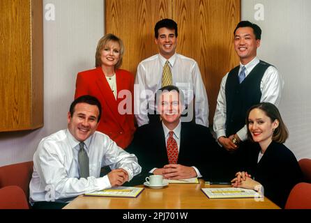 1996 GRUPPO STORICO DI IMPIEGATI CHE SI RIUNISCONO INTORNO AL TAVOLO Foto Stock