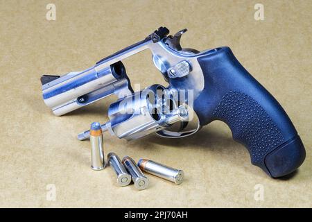 La pistola a revolver compatta, in acciaio inox J-Frame M60 pistola vista posteriore lato sinistro, con cilindro aperto preparare per l'uso isolato su sfondo marrone. Foto Stock