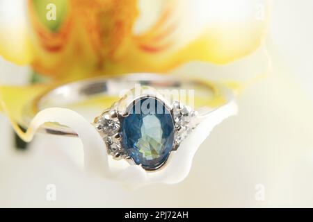 anello in oro bianco con diamanti si trova su una foto macro orchidea fiorente Foto Stock